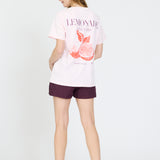 Person wearing a white t-shirt with a graphic design and purple shorts on a white background