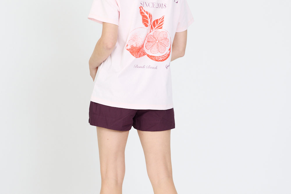 Person wearing a white t-shirt with a graphic design and purple shorts on a white background