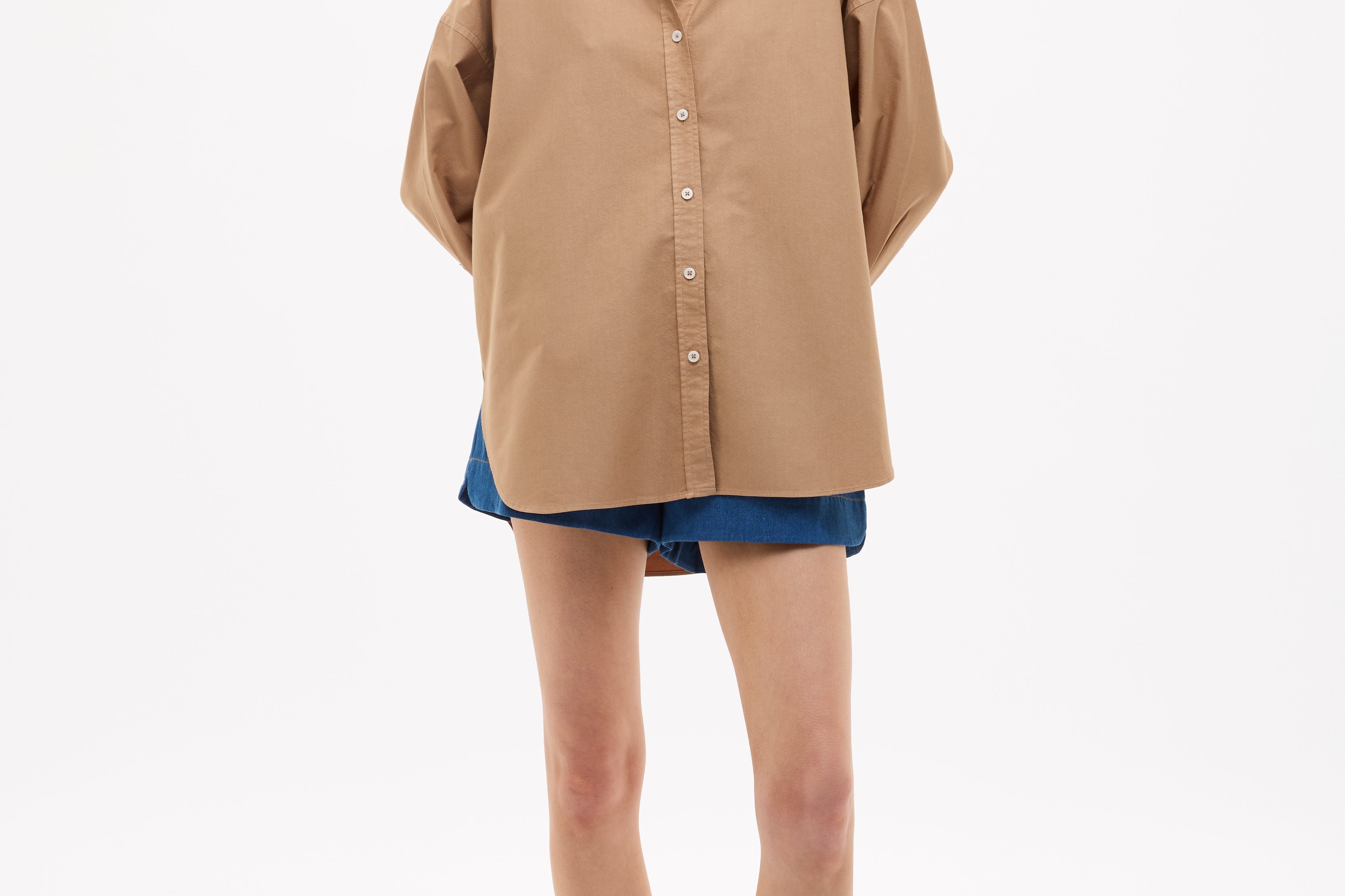 Woman wearing Mara Oversized Long Sleeve Shirt - Toffee in a relaxed fit paired with denim shorts and sandals