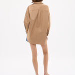 Woman wearing Mara Oversized Long Sleeve Shirt - Toffee in a relaxed fit, shown from behind on a white background.