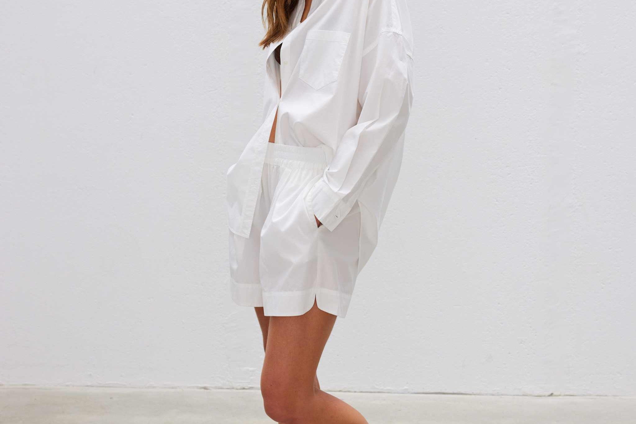 Woman wearing a relaxed fit white long sleeve shirt made from 100% organic cotton with curved hem and drop shoulder