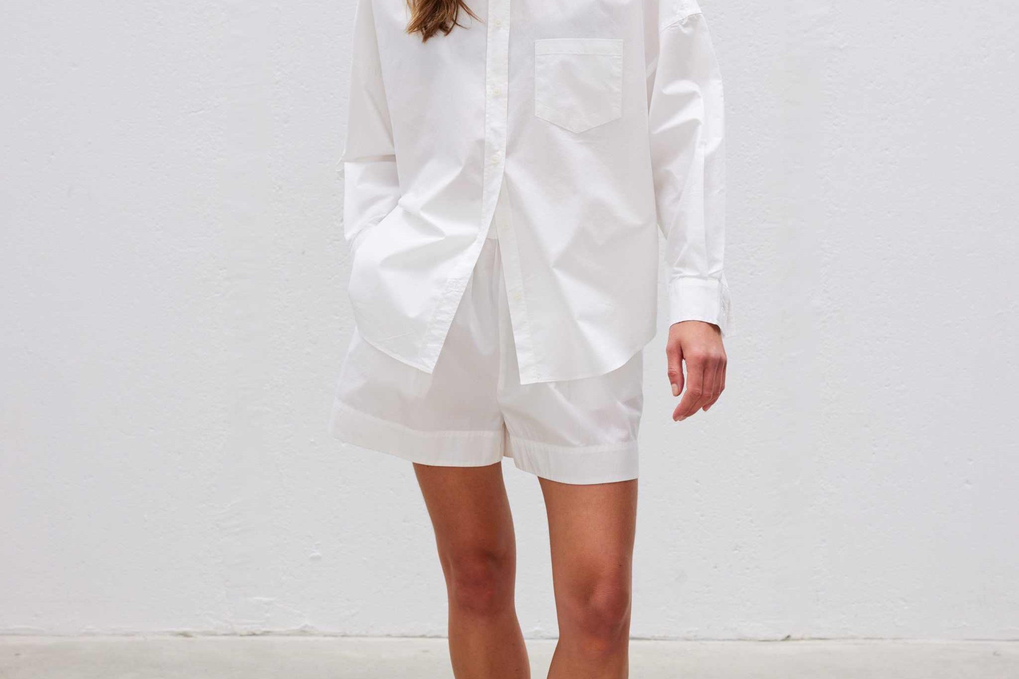 Woman wearing relaxed fit white long sleeve shirt made from 100% organic cotton with custom buttons and curved hem