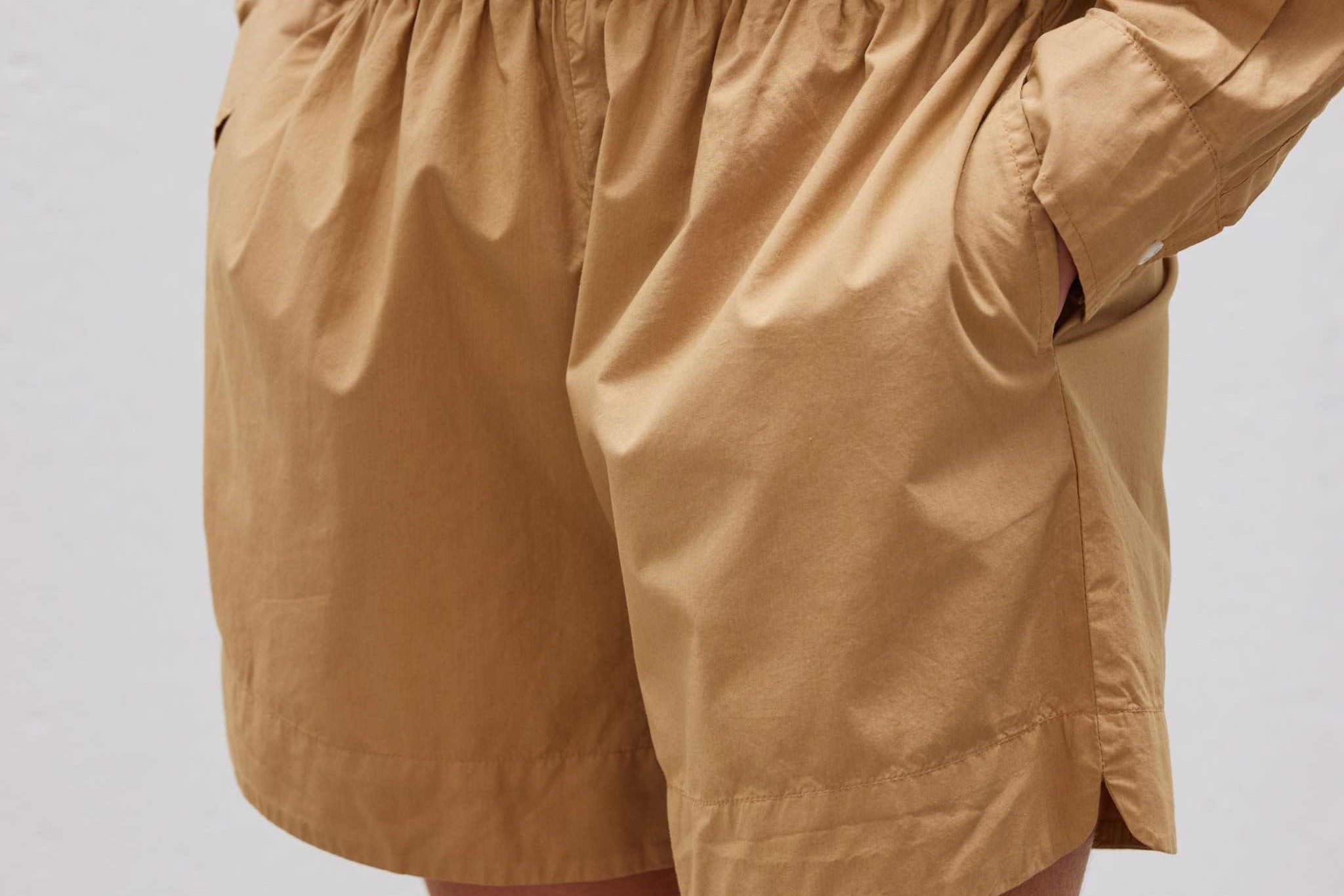 Close-up of person wearing toffee-colored Chiara long sleeve shirt and matching shorts with relaxed fit and elastic waistband