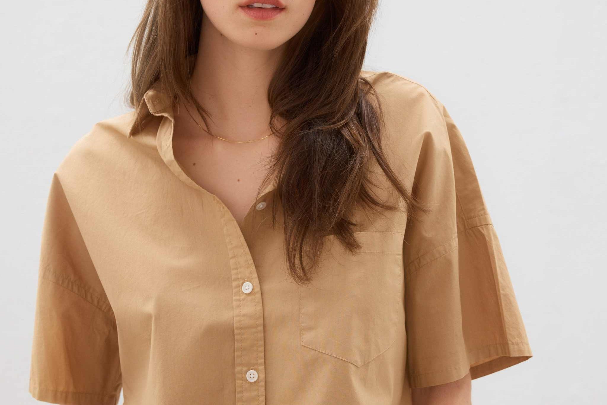 Woman wearing a toffee-colored cotton button-up short sleeve shirt with a relaxed fit and chest pocket